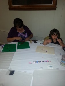 Grandmother and granddaughter making prayer beads.